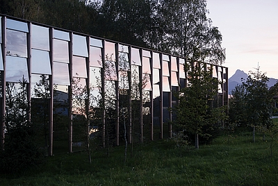Außenansicht Grüne Erde Welt in Grünau im Almtal: eine gläserne Fasade integriert sich in die Landschaft. © Grüne Erde GmbH