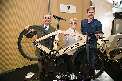 Zwei Männer und eine Frau halten ein Fahrrad