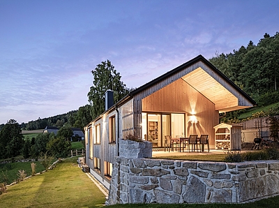 Beleuchtetes Holzhaus mit Terrasse in der Dämmerung Fotos: Buchner/Lumina