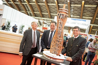 3 Besucher der Holzmesse Klagenfurt bestaunen ein Objekt aus Holz ©Kärntner Messen / Zangerle